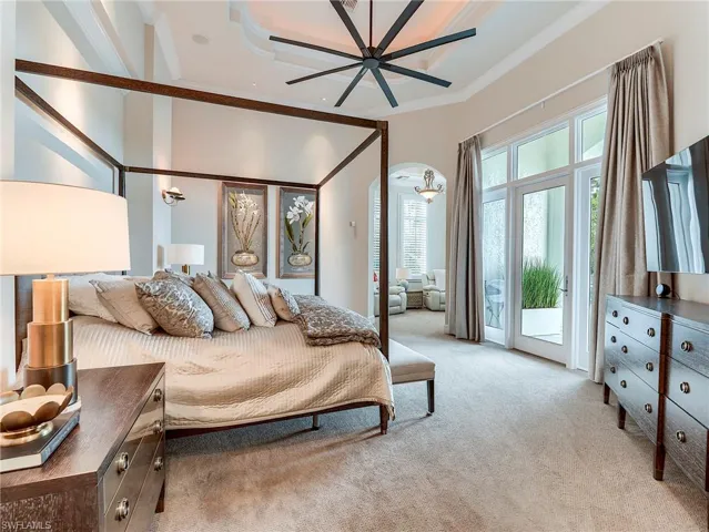 Ground level master bedroom, access to exterior, light colored carpet, ceiling fan, and arched walkways, kitchenette.