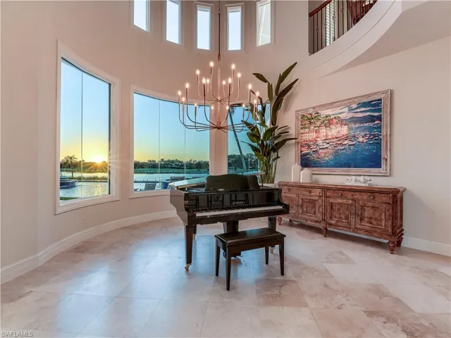 Dining room with plenty of natural light, a chandelier, a towering ceiling, and a water view