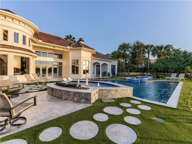 View of pool with a patio, a pool with connected hot tub, and a lawn