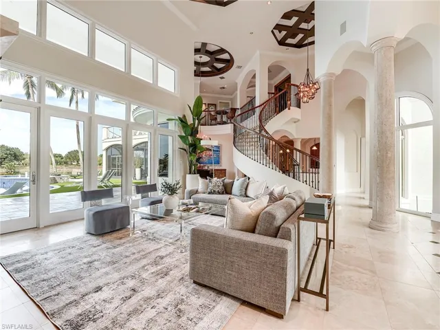 Living room with a chandelier, a high ceiling, stairway, crown molding, and decorative columns