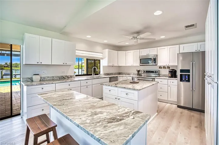 Kitchen featuring stainless steel appliances, a kitchen island, and light granite counters