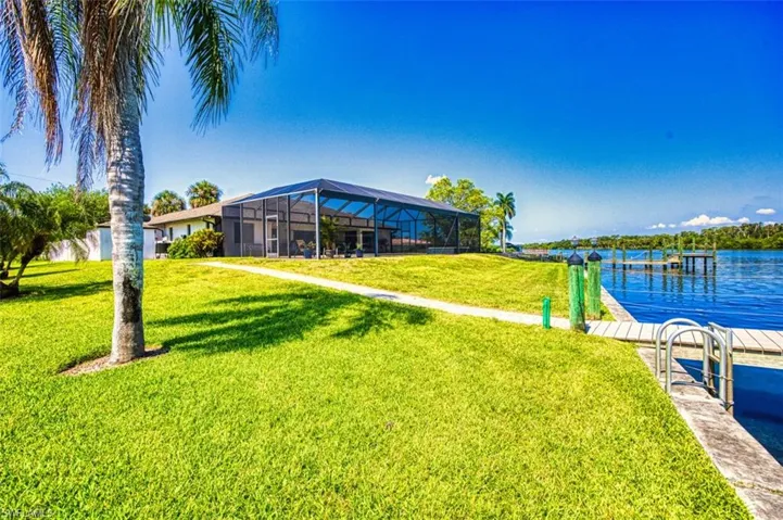 Dock area with a yard, a water view, and glass enclosure