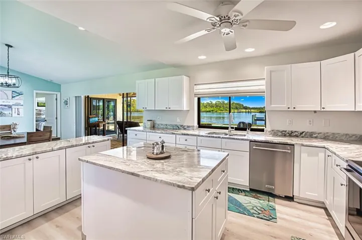 Kitchen featuring stainless steel appliances, a center island, a sink, light wood finished floors, and lofted ceiling