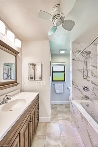 Full bath featuring a textured ceiling, vanity,  shower combination, ceiling fan, and baseboards