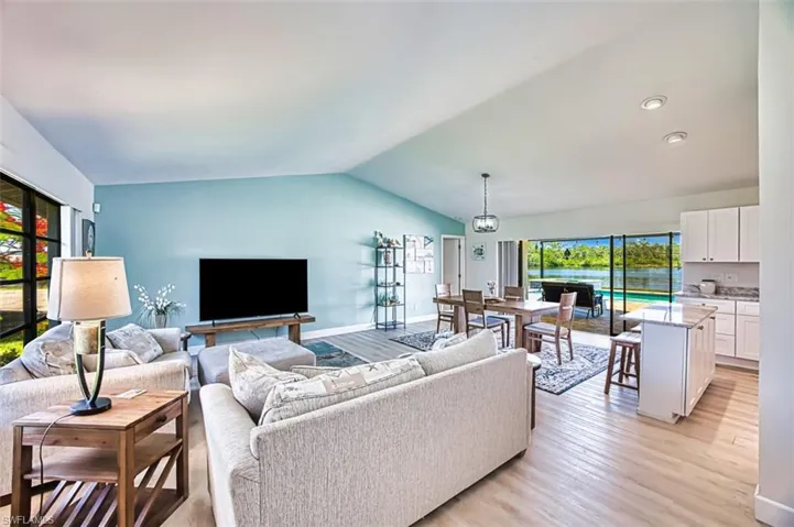 Living area featuring light luxury vinyl flooring, vaulted ceiling, and recessed lighting