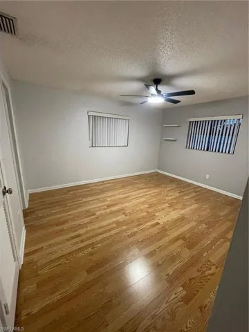 Empty room featuring light wood-type flooring, a textured ceiling, and ceiling fan
