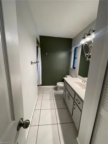 Full bath featuring vanity, a textured ceiling, tile patterned floors, and a shower with shower curtain