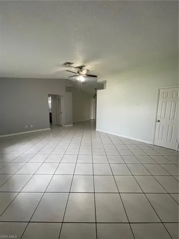 Unfurnished living room with a textured ceiling, ceiling fan, and light tile patterned floors