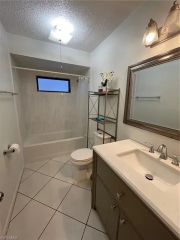 Full bathroom featuring a textured ceiling, vanity, shower / tub combo with curtain, and tile patterned floors