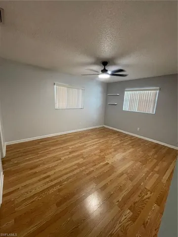 Empty room featuring light wood-type flooring, a textured ceiling, and a ceiling fan