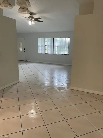 Unfurnished room with light tile patterned floors, a textured ceiling, and a ceiling fan