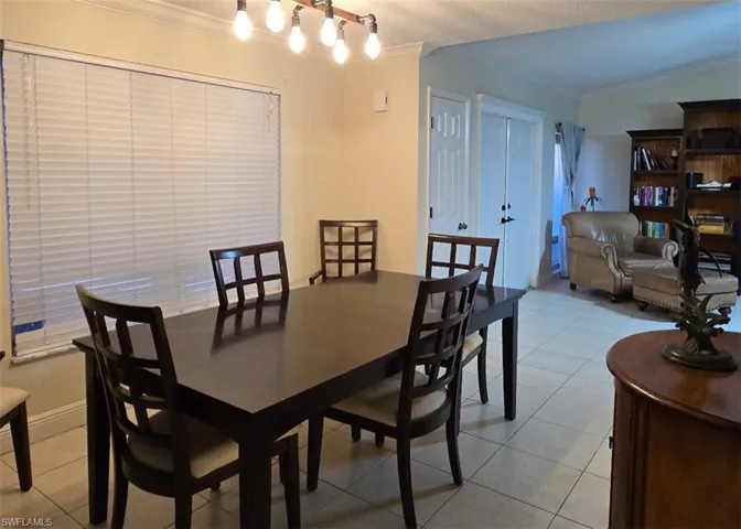 Dining room featuring light tile patterned flooring, crown molding, and a textured ceiling