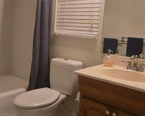 Bathroom featuring vanity, a textured wall, and shower / bathtub combination with curtain