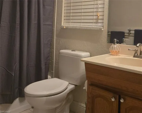 Bathroom featuring a textured wall, vanity, and a shower with curtain