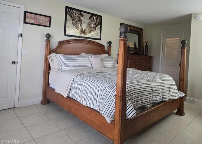Bedroom with a textured ceiling, light tile patterned floors, and a closet