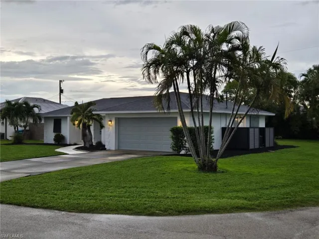 Ranch-style house with concrete driveway, a front lawn, an attached garage, and roof with shingles