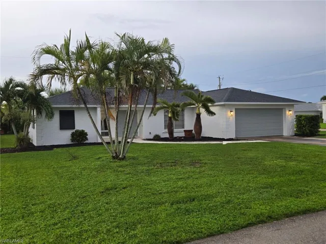 Ranch-style home featuring roof with shingles, a front yard, concrete driveway, and a garage