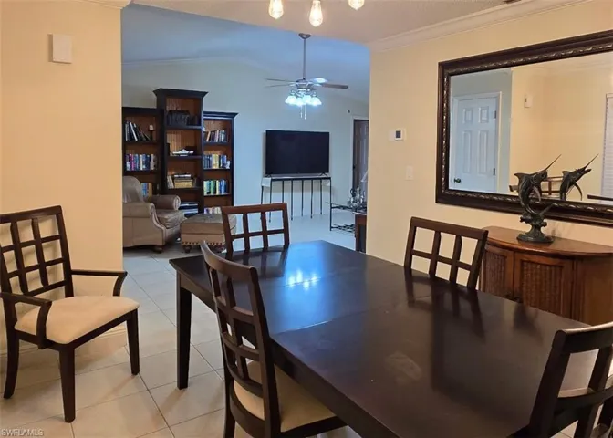 Dining room featuring crown molding, light tile patterned floors, a ceiling fan, and vaulted ceiling