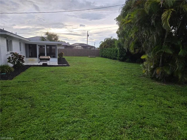 Yard at dusk featuring a sunroom and a fenced backyard