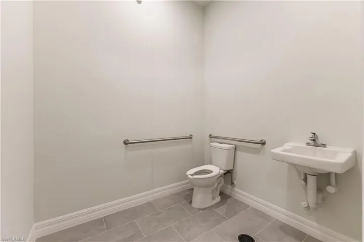 Half bath with light tile patterned floors and baseboards