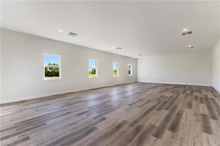 Unfurnished living room with light wood-type flooring, healthy amount of natural light, and recessed lighting