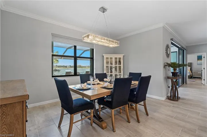 Dining area with an inviting chandelier, wood finish floors, crown molding, and baseboards