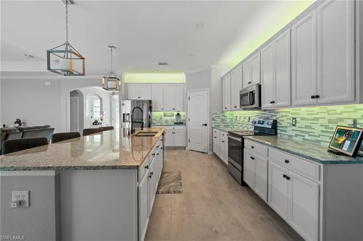 Kitchen featuring arched walkways, a sink, crown molding, and appliances with stainless steel finishes