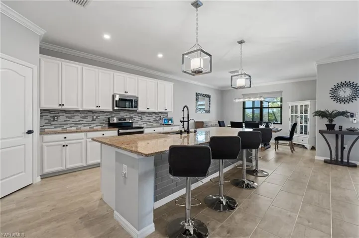 Kitchen with a kitchen bar, appliances with stainless steel finishes, a sink, light stone counters, and backsplash