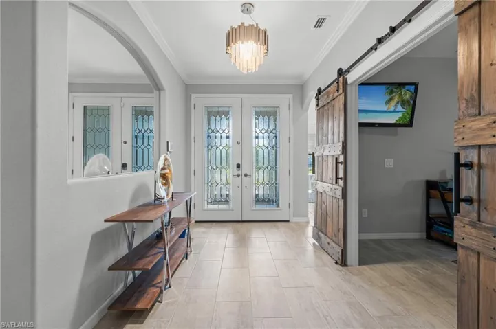 Entryway with arched walkways, ornamental molding, visible vents, and french doors