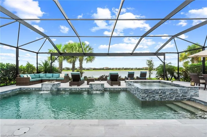 View of swimming pool with glass enclosure, a pool with connected hot tub, a patio area, outdoor lounge area, and a water view