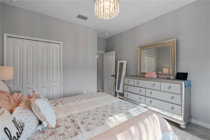 Bedroom with a closet, baseboards, visible vents, and a notable chandelier