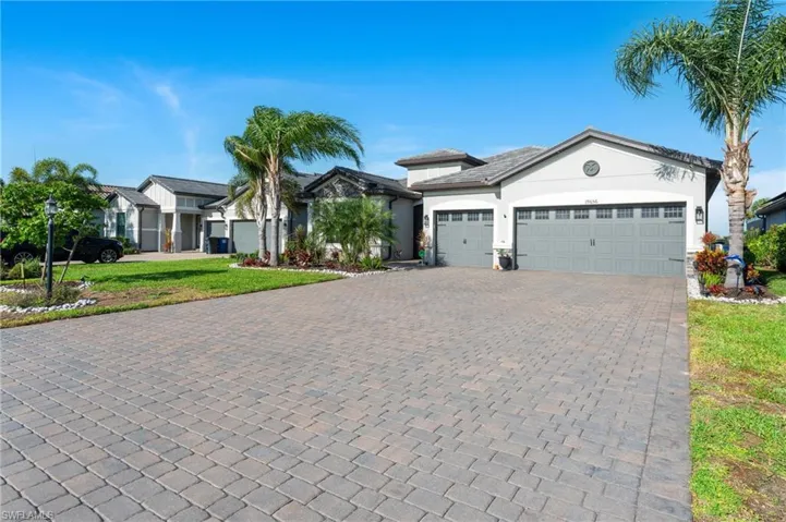 View of front of property featuring a front yard, decorative driveway, stucco siding, and an attached garage