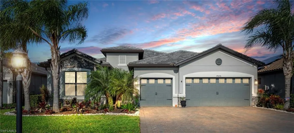 View of front of property with decorative driveway, stucco siding, an attached garage, and stone siding