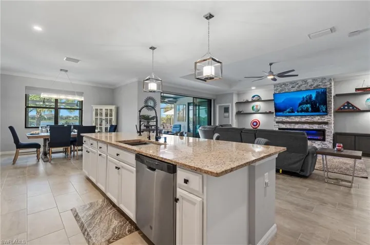 Kitchen with dishwasher, ceiling fan, light stone countertops, built in features, and a sink