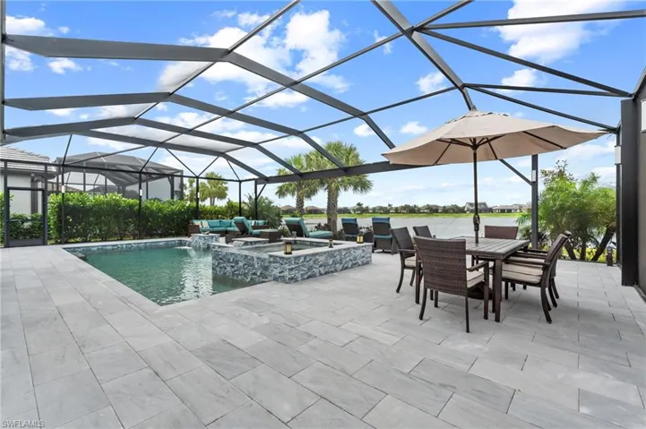 View of pool featuring an outdoor hangout area, a pool with connected hot tub, glass enclosure, outdoor dining area, and a patio area