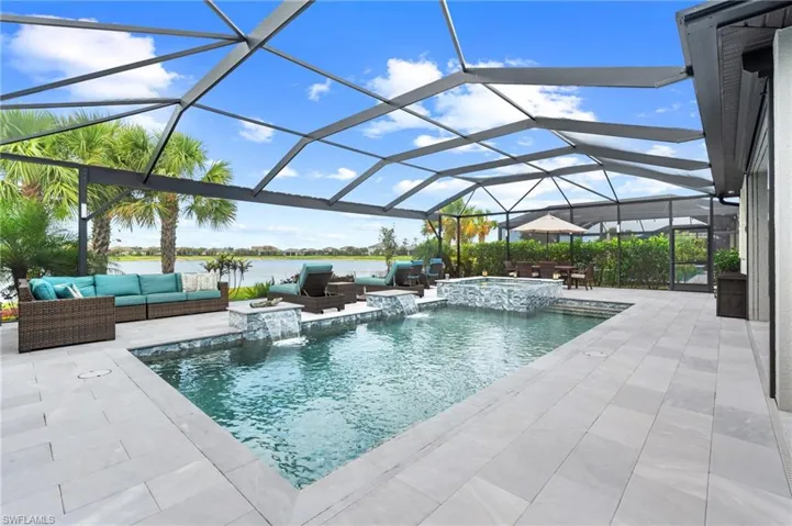 View of pool with a patio, a water view, glass enclosure, a pool with connected hot tub, and outdoor lounge area