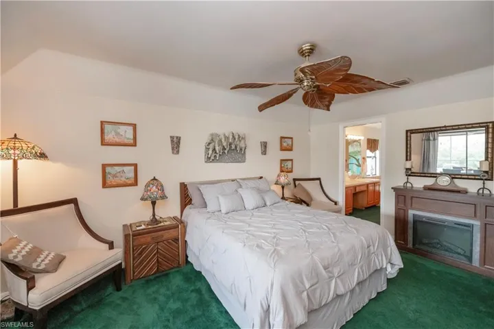 Carpeted bedroom featuring ensuite bath and ceiling fan