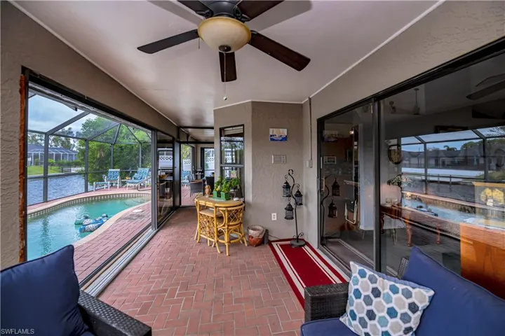 Sunroom with a swimming pool, a water view, and ceiling fan