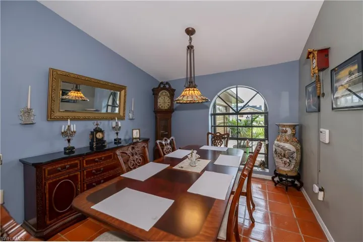 Tiled dining room featuring vaulted ceiling