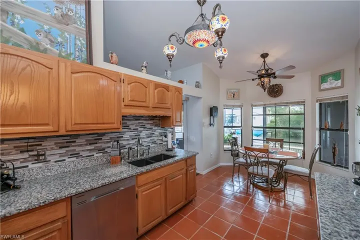 Kitchen featuring decorative backsplash, dishwasher, hanging light fixtures, and vaulted ceiling