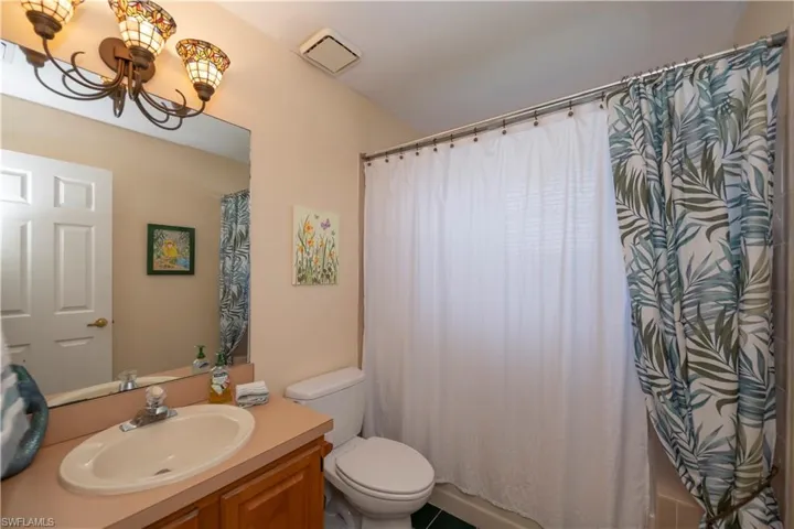 Bathroom with vanity, a shower with curtain, and toilet
