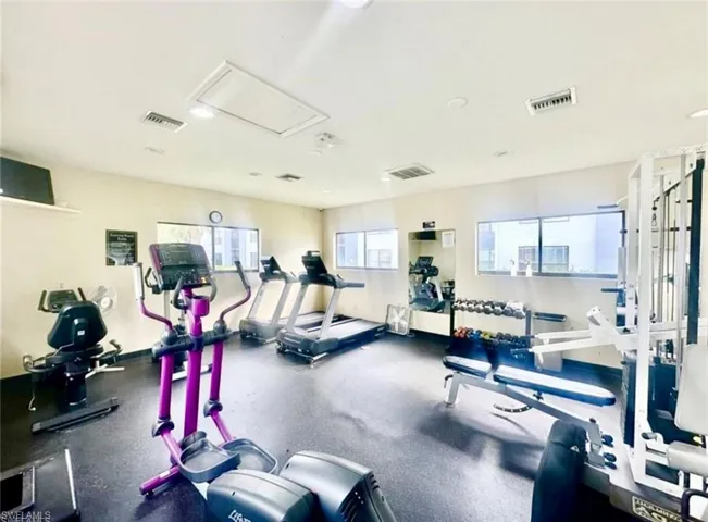 Fitness center featuring rubberized flooring, multiple windows, and recessed lighting