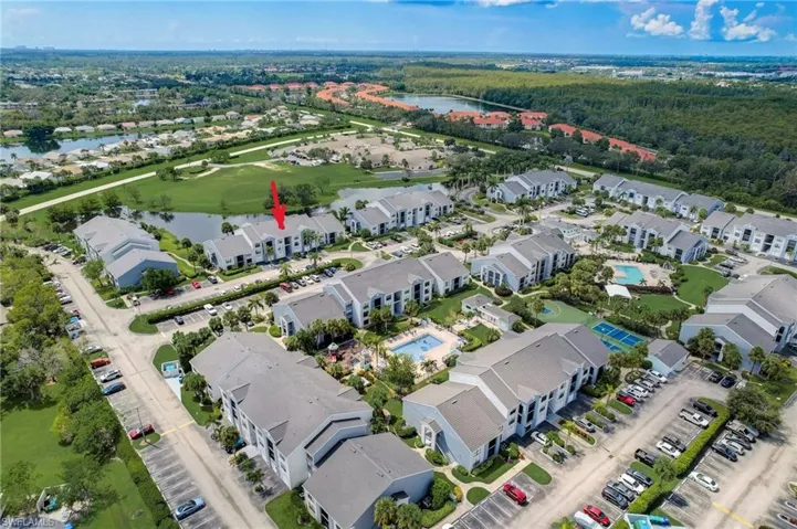 Aerial perspective showcasing a residential community with multiple multi-story buildings, surrounded by green spaces and water features