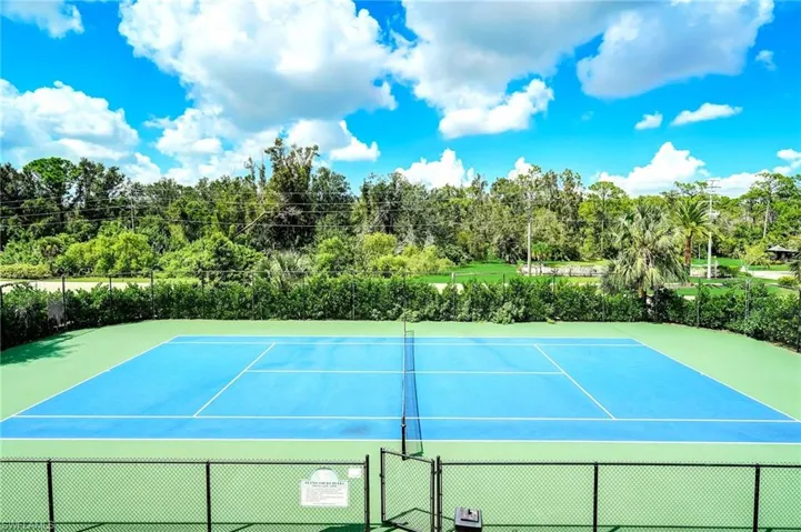 Full-sized tennis court featuring a blue playing surface with white line markings, green perimeter, and a black net