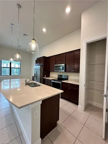 Kitchen with pendant lighting, sink, an island with sink, appliances with stainless steel finishes, and light tile patterned floors