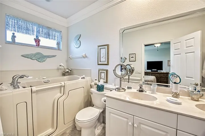Bathroom featuring double sink vanity, toilet, a bathtub, and crown molding