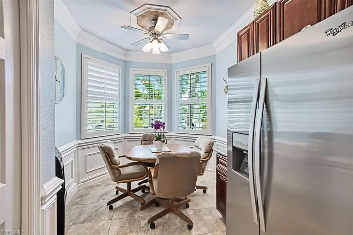 Dining space with ceiling fan, crown molding, and light tile flooring