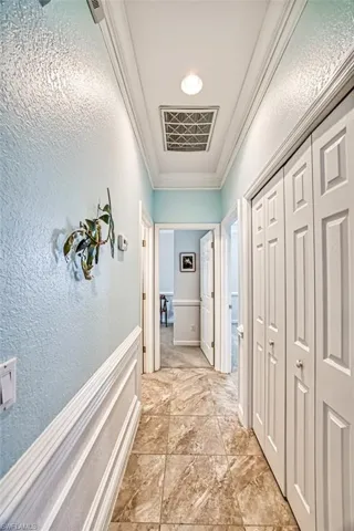 Corridor featuring crown molding and light tile floors