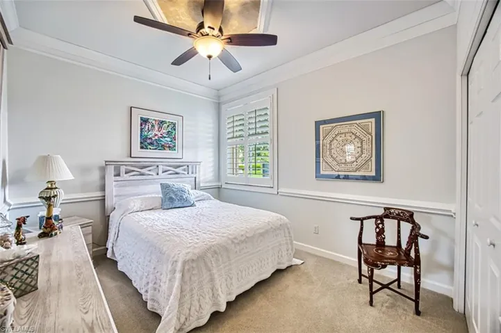 Carpeted bedroom with a closet, ceiling fan, and crown molding