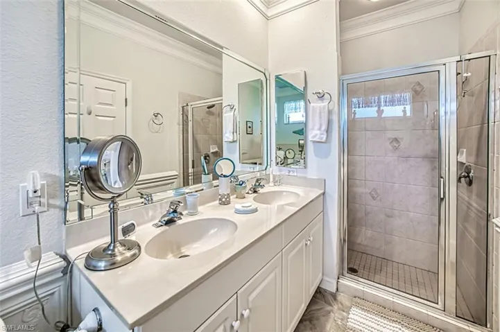 Bathroom with crown molding, double sink, an enclosed shower, tile floors, and large vanity
